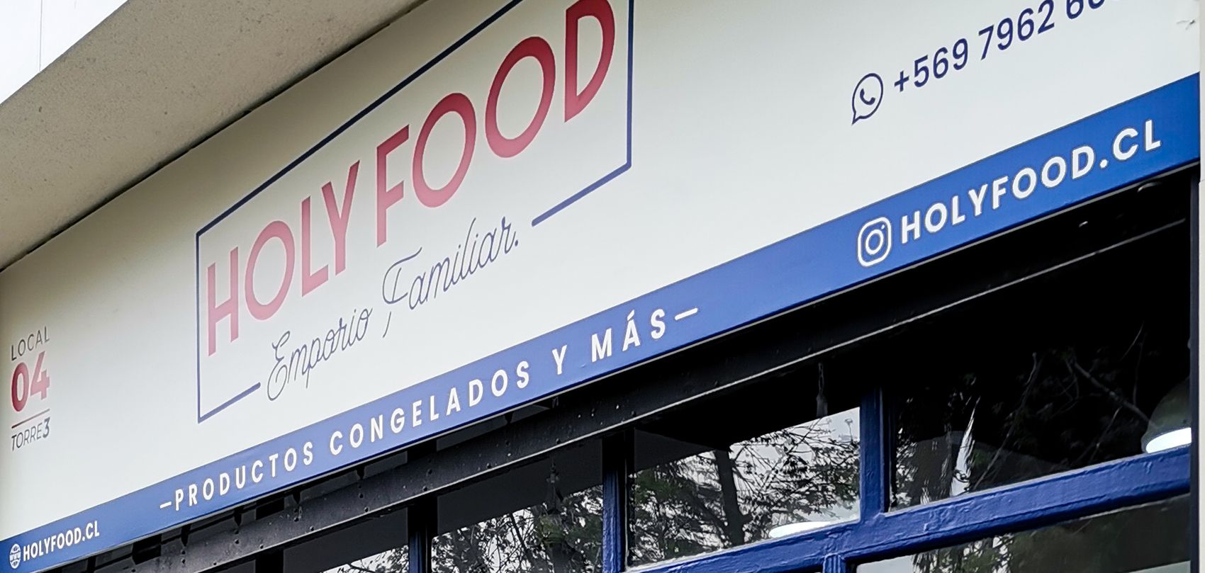 Letrero exterior de Holy Food con el logotipo y la bajada Emporio Familiar